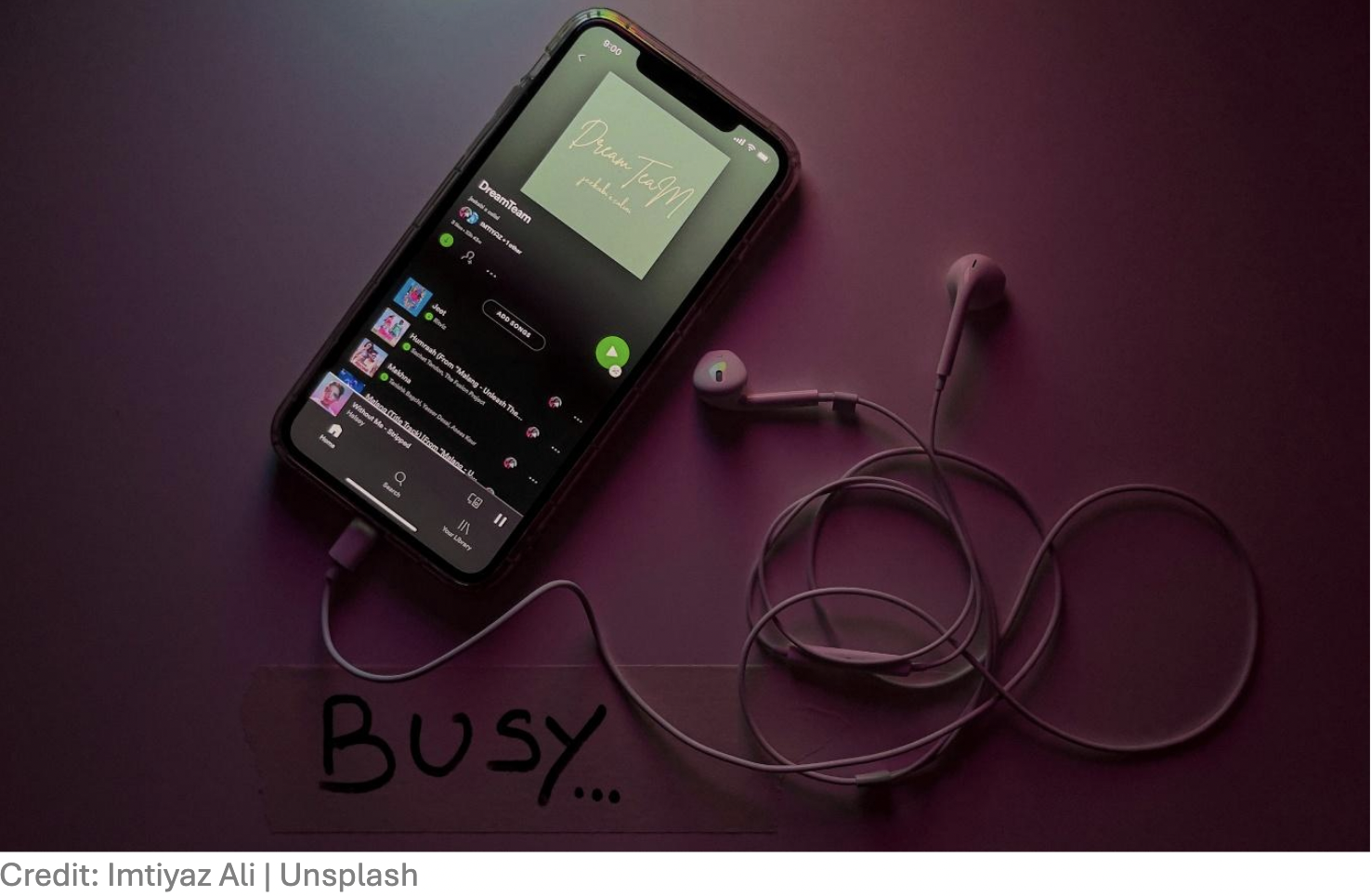 Phone with music playlist displaying and headphones plugged in to the phone